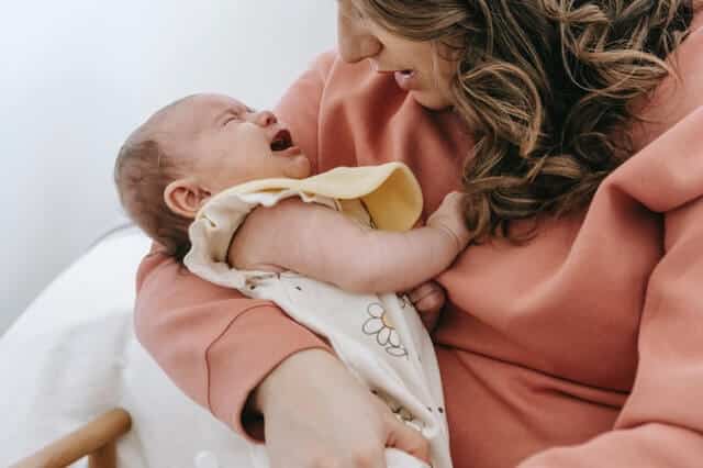 Der erste Schnupfen - Mama mit weinendem Baby auf dem Arm