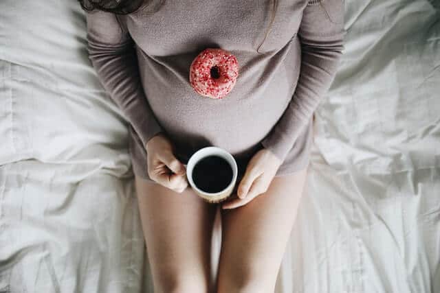 Kaffee in der Stillzeit – Schwangere Frau im Bett mit Kaffee in den Händen
