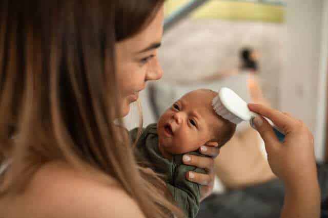 Babypflege - Mutter kämmt Säugling