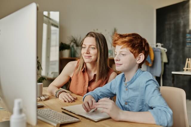 Englisch für Kinder - Mutter sitzt mit Sohn am Computer