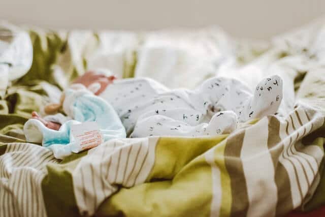 Impfen Baby - Baby liegt auf dem Bett