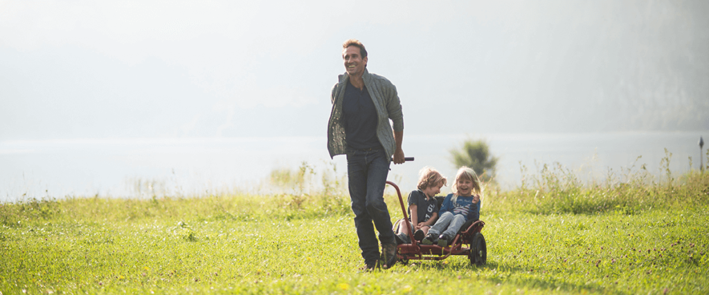 YippieYo Crossbuggy - Vater mit zwei Kindern im Cross Buggy laufen über Wiese