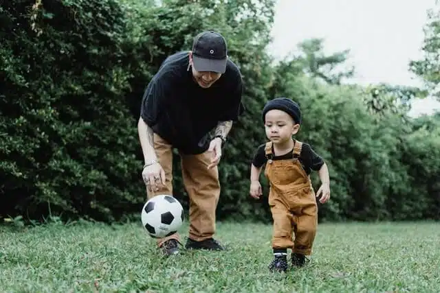 Achtsamkeit - Vater spielt mit Sohn im Garten Fußball