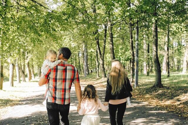 Rechtsschutzversicherung - Eltern mit zwei Kindern spazieren in Park