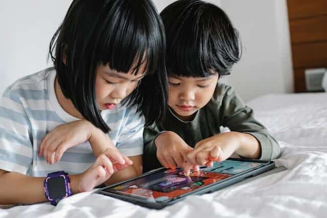 Medienkonsum - Junge und Mädchen spielen auf Tablet