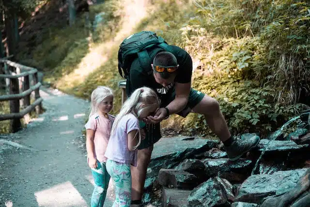 wandern_mit_kindern_vater_und_toechter_trinken_aus_bergfluss